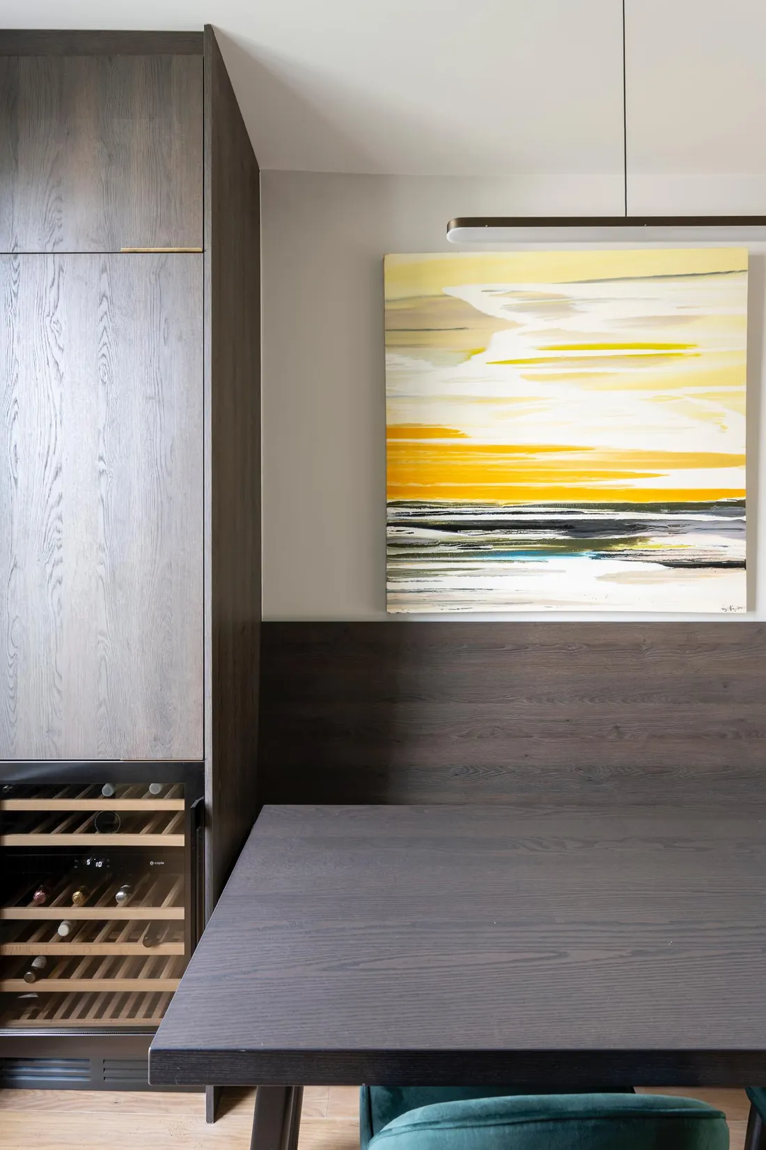 Built-in banquette with dark oak panelling beside tall kitchen units and a wine fridge