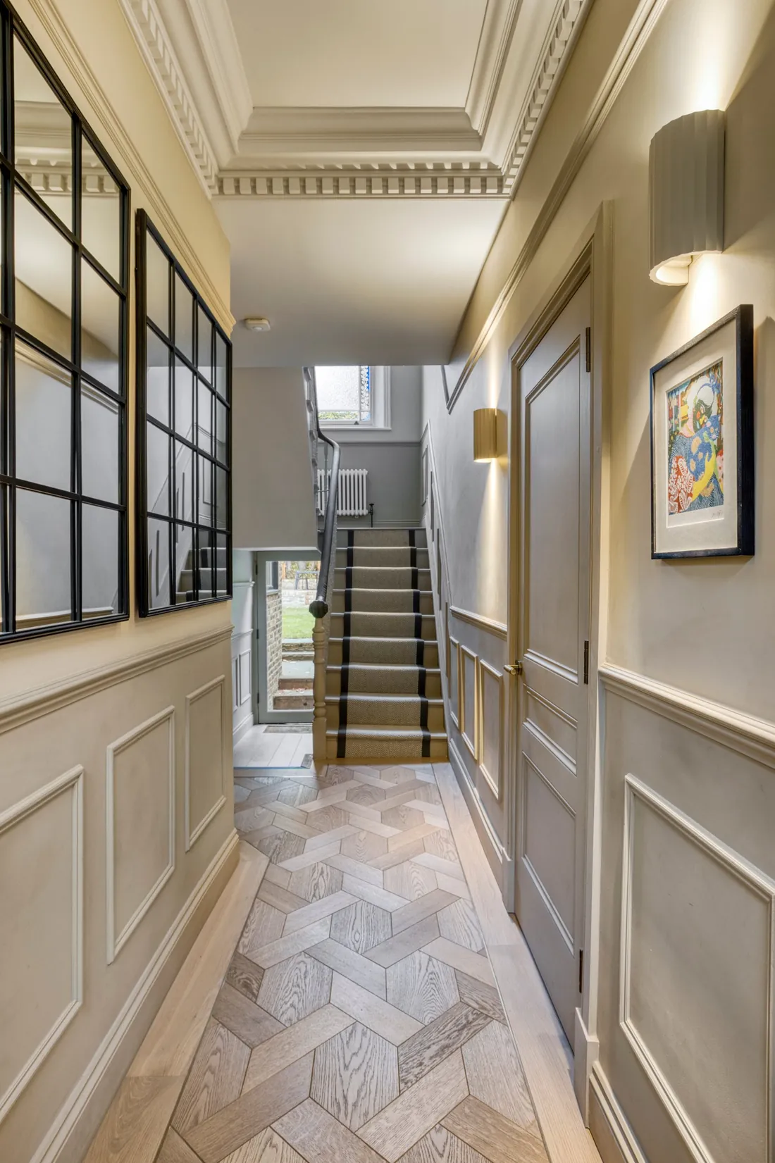 Panelled hallway with decorative cornicing, a parquet floor and a stair runner