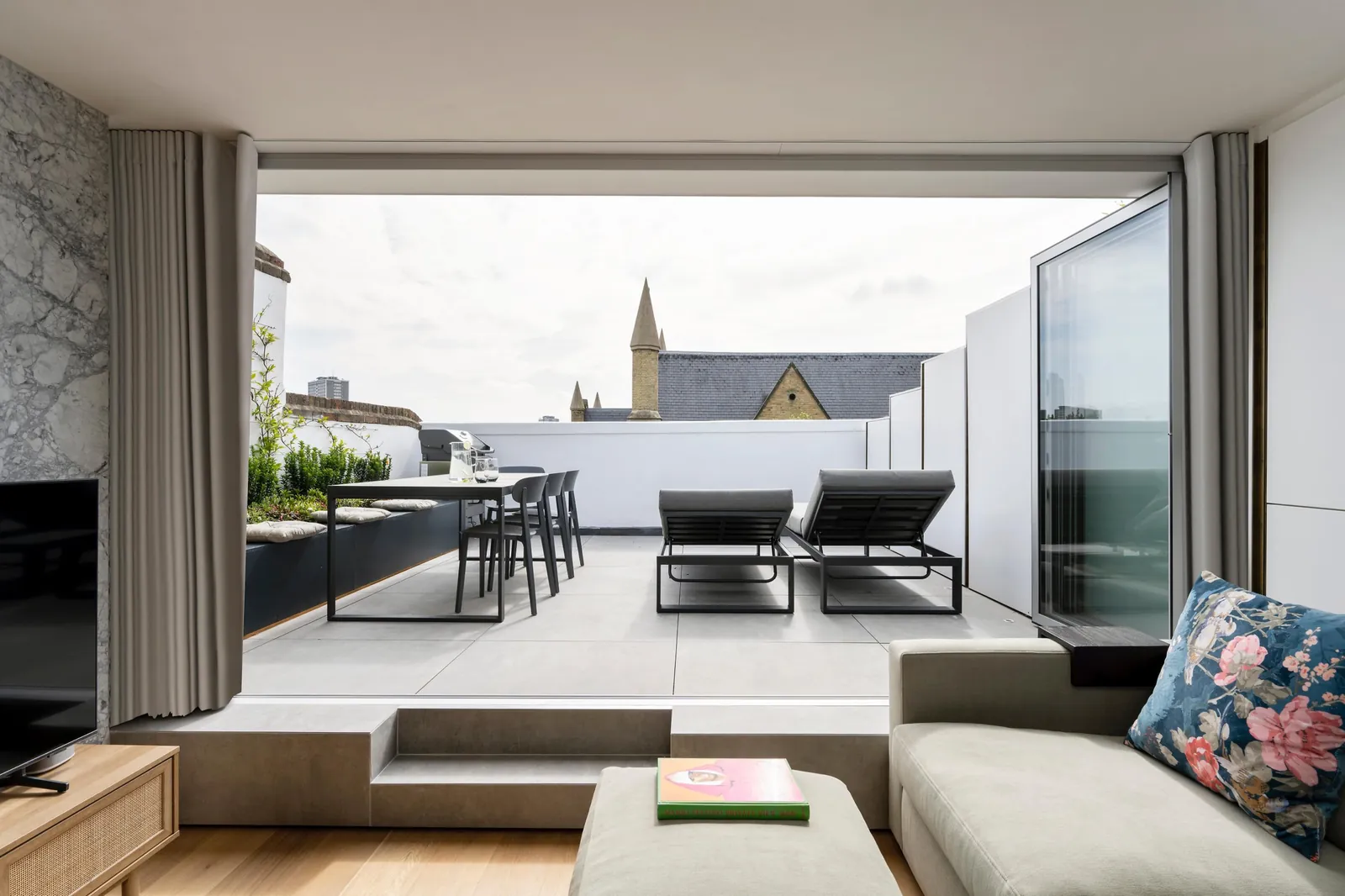 View from the loft sofa up the steps to the roof terrace, with a dining table and two loungers