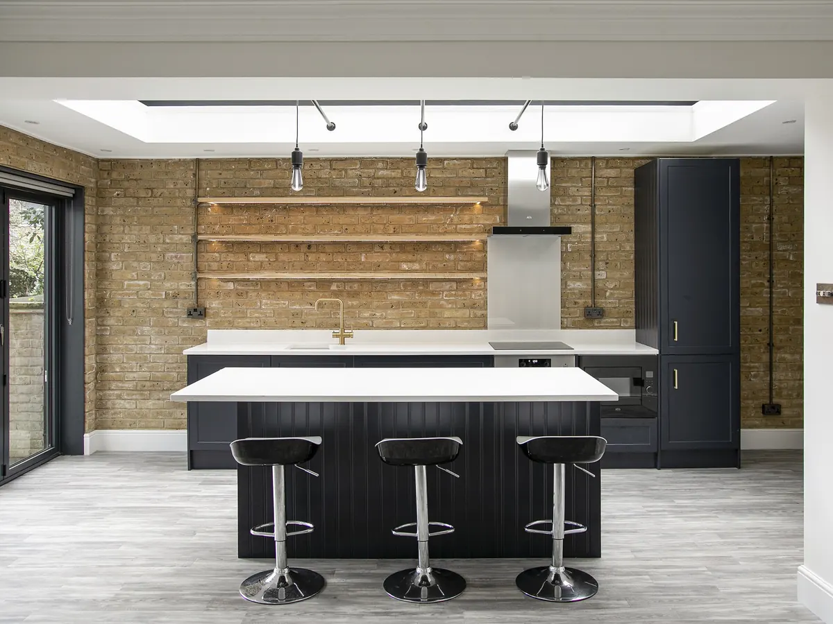 Rear kitchen extension with a large rooflight, exposed London stock brick wall, navy shaker kitchen and island